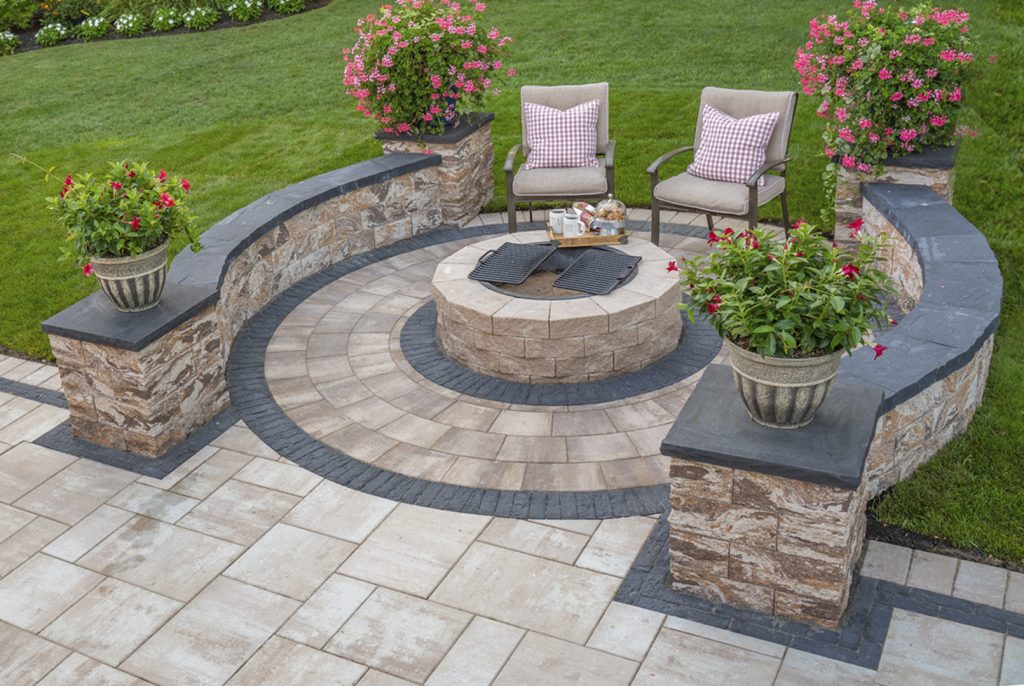 Affordable patio A stone sitting wall edged with plants divides a sloping yard into usable tiers.