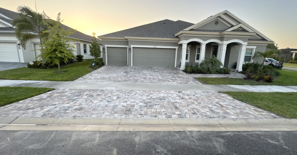 Residential driveway featuring tan and gray interlocking pavers, showing one of the best pavers for driveways in Florida homes.