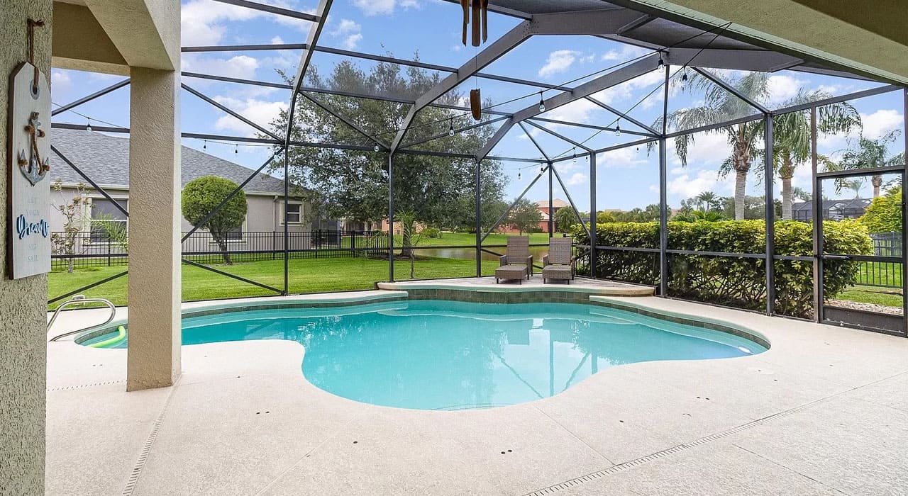 Curved swimming pool under a screened patio enclosure, highlighting a completed project that inspires Florida homeowners planning a DIY pool screen enclosure.