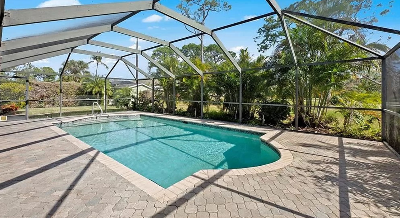 Backyard pool area with paver deck and screened structure, offering a practical example of a DIY pool screen enclosure for Florida homes