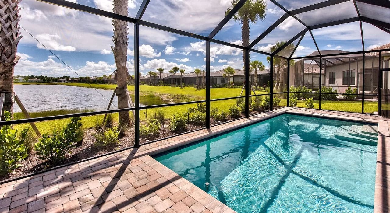 Pool cage enclosure overlooking a lake, showing the results of a durable and stylish pool screen installation for Florida homes.