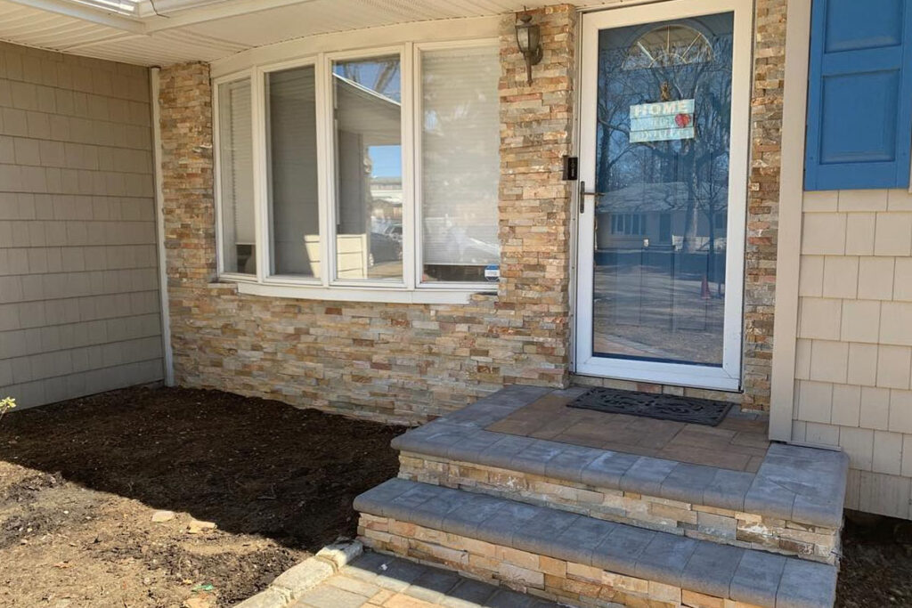 Front porch with stone veneer and two-step paver stoop built during a professional paver steps installation by Affordable Patio in Suffolk County.