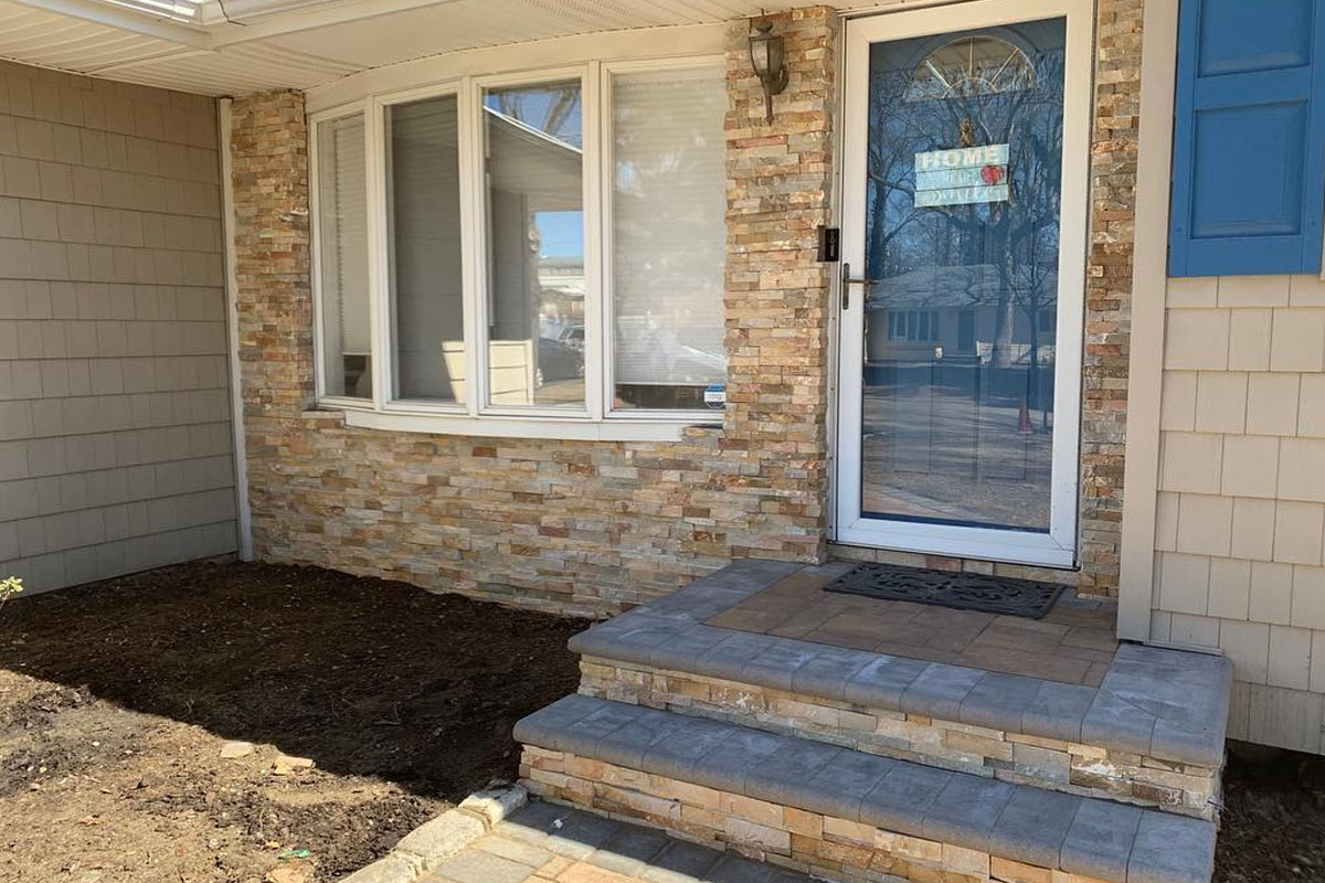 Front porch with stone veneer and two-step paver stoop built during a professional paver steps installation by Affordable Patio in Suffolk County.