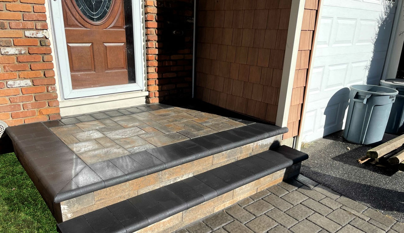 Modern entryway featuring dark bullnose coping and a compact landing area created through expert paver steps installation.