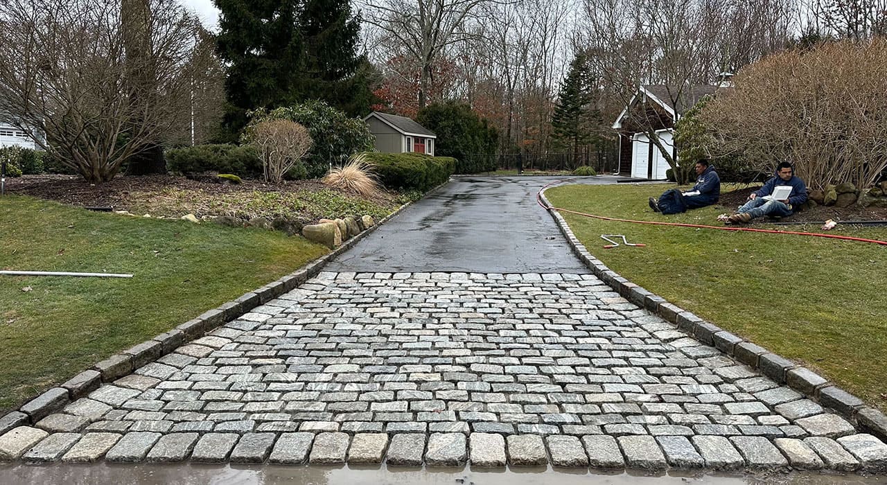 Cobblestone-style paver driveway entrance featuring strong, weather-resistant materials, ideal for homeowners seeking the best pavers for driveways in New Hampshire