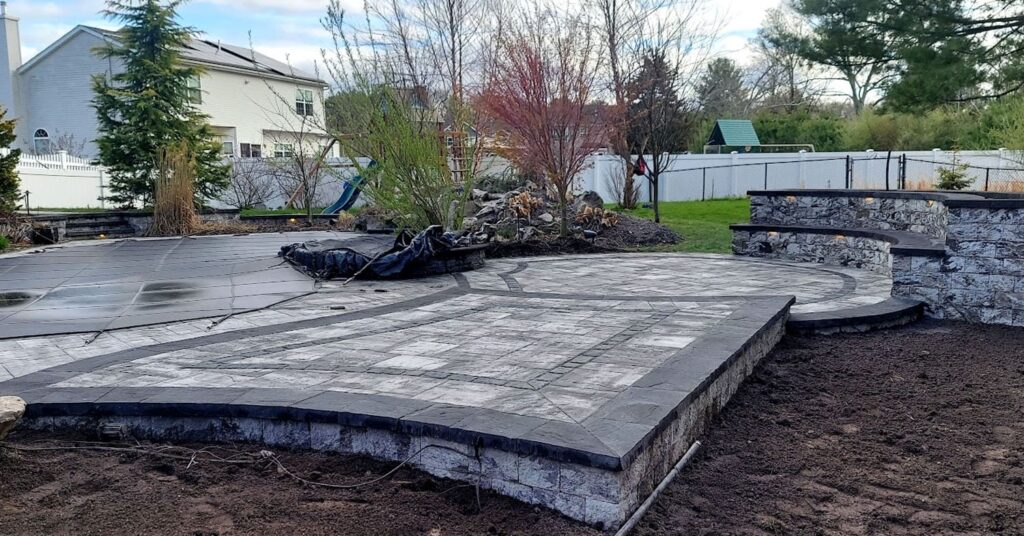 Backyard patio with stone retaining wall and steps, showing a clean outdoor space after following expert tips on how to clean patio pavers.