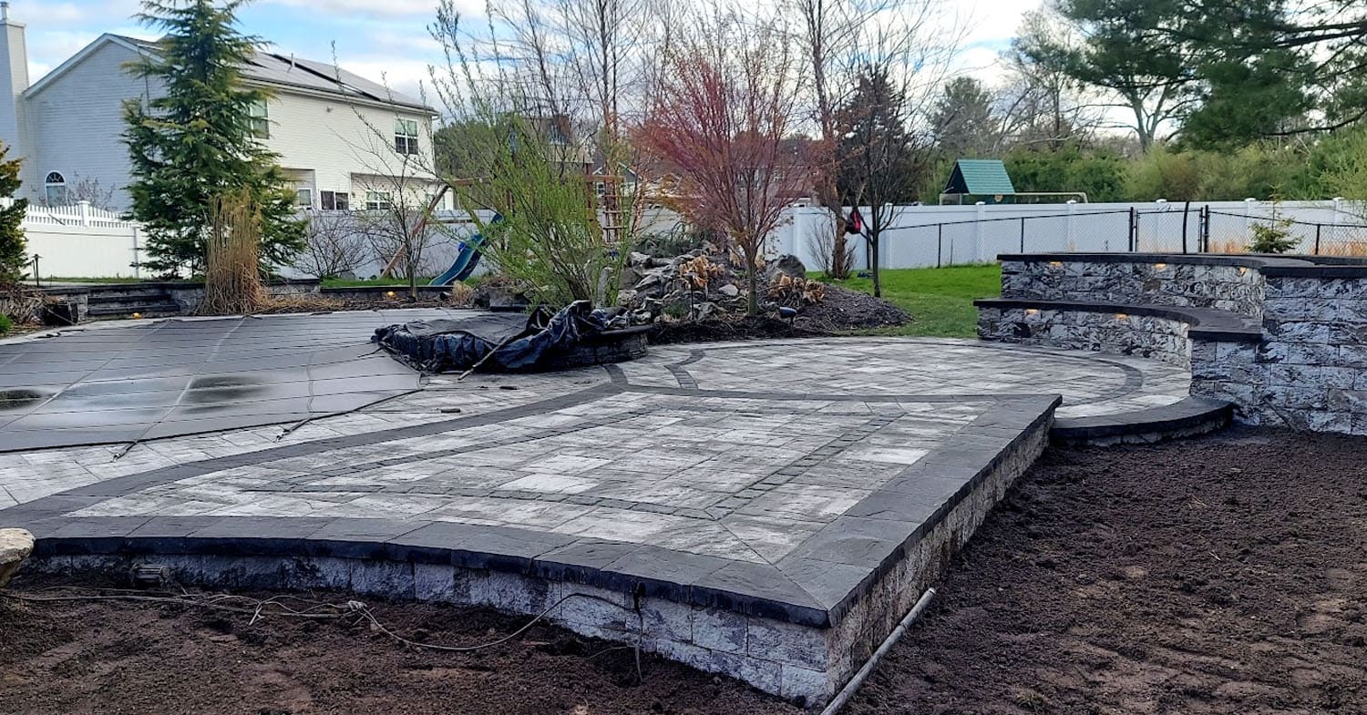 Backyard patio with stone retaining wall and steps, showing a clean outdoor space after following expert tips on how to clean patio pavers.