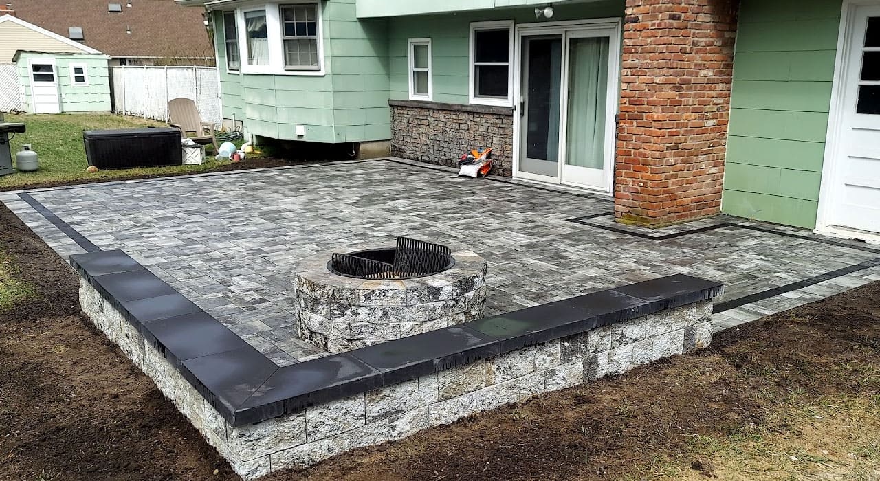 Gray paver patio and circular stone fire pit combination, offering inspiration for durable backyard fire pit design ideas across New Hampshire
