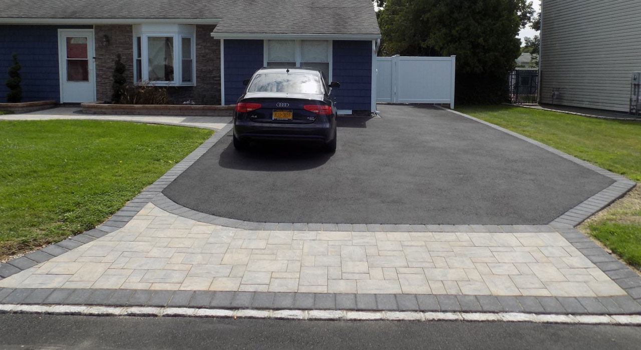 Residential driveway with paver apron and asphalt surface demonstrating professional installation that meets standard sizes for walkways, stoops, and 2-car driveways.
