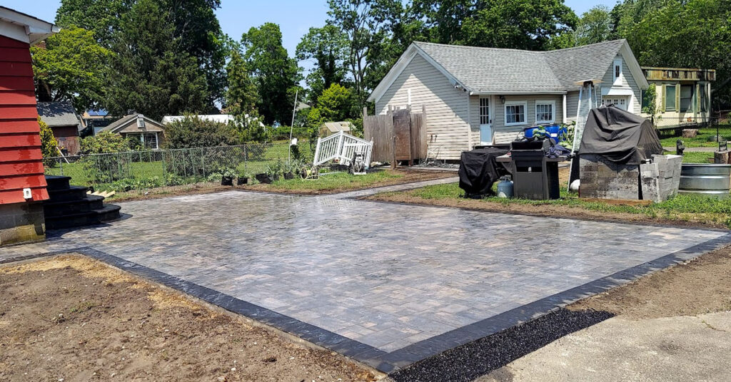 Completed paver driveway with clean borders, smooth surface, and finished grading around surrounding residential property.