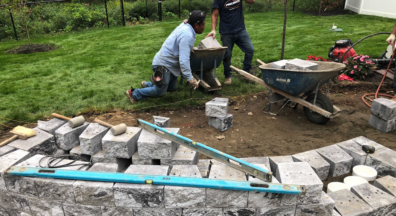 Skilled craftsmen meticulously lay heavy stone blocks to create a durable, custom outdoor kitchen.