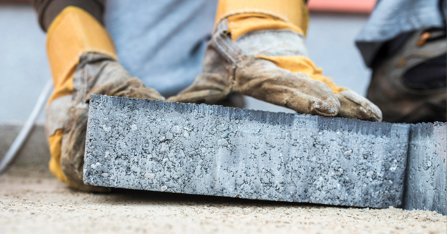 Close-up of gloved hands precisely placing a concrete paver.