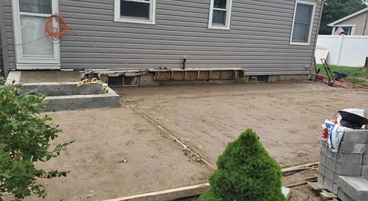 Prepared dirt foundation for a patio next to a house.