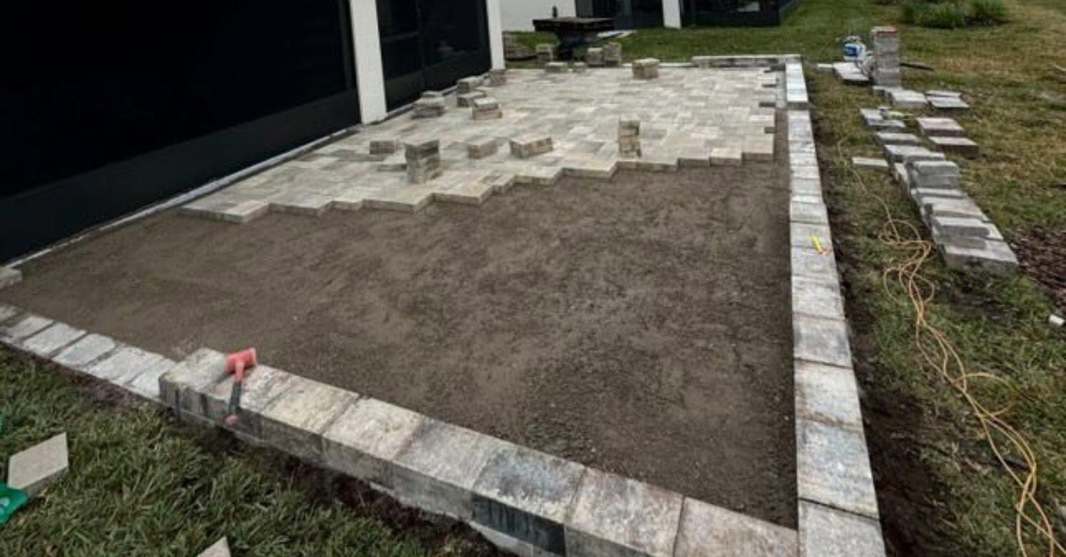 Professional installation of affordable patios in Florida, showing a base layer of sand and pavers being carefully laid by Affordable Patio Florida.