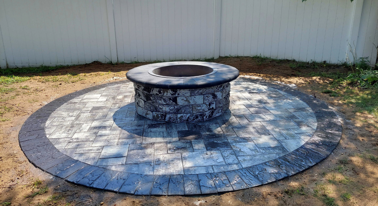 Elegant circular stone inlay surrounding a matching backyard fire pit, showing high-end options for the cost to install a fire pit.