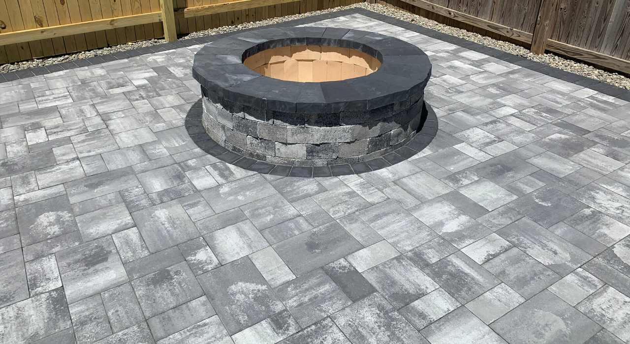 Detail of a professionally constructed masonry fire pit on a modern paver surface, highlighting the cost to install a fire pit.