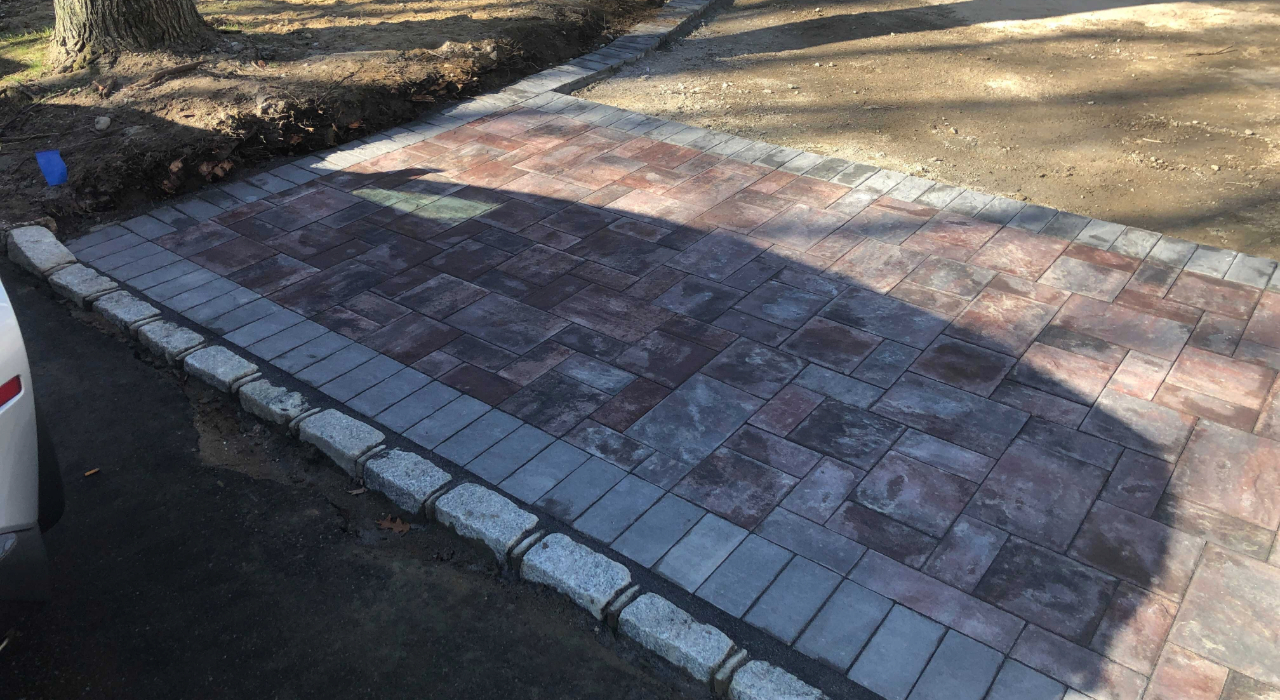 Newly installed multi-colored paving stones with a granite border, showcasing the results of choosing the right patio contractor.