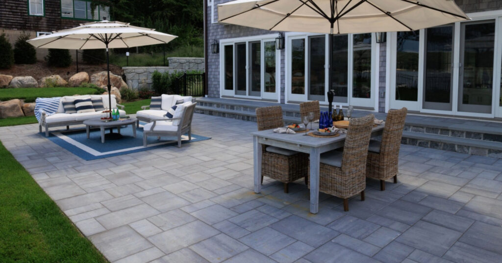 A luxury stone terrace featuring a dining set and lounge chairs, perfect for choosing the right patio contractor.