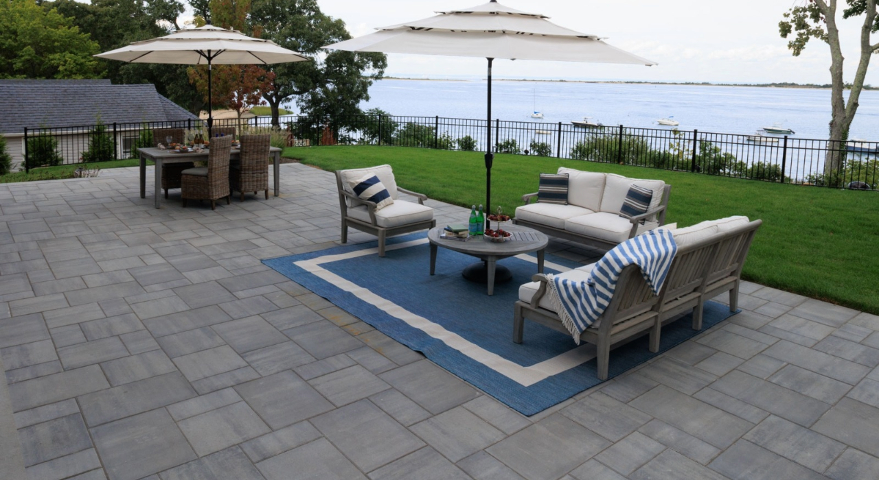 Large modern stone patio with coastal views and elegant outdoor furniture, ideal when choosing the right patio contractor.
