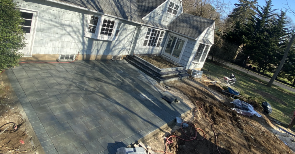 Professional stone installers completing a backyard project, showing how long does it take to install a paver patio.