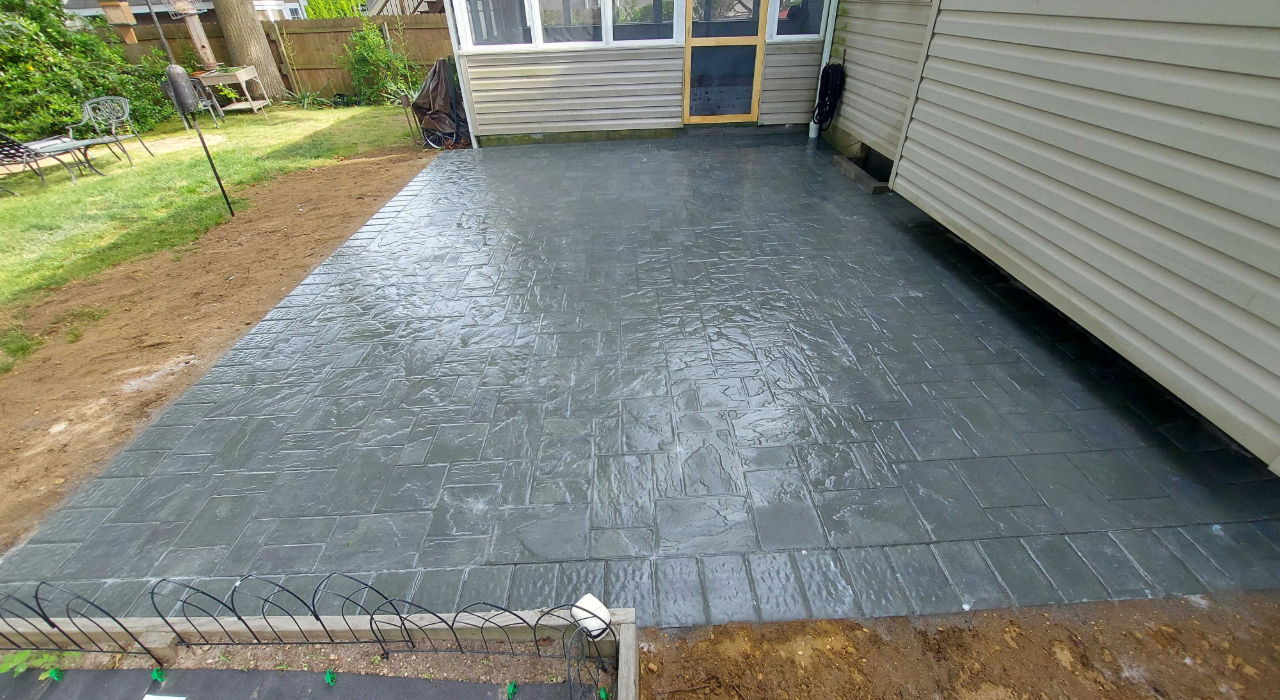 View of a wet, textured stone backyard surface, a key factor in how long does it take to install a paver patio.