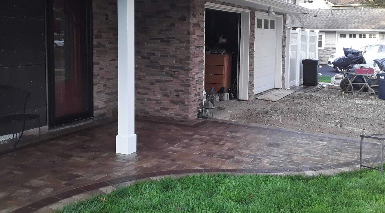 A wide, dark-toned masonry front porch and path integrated into a home entrance, highlighting the cost to install paver walkway.