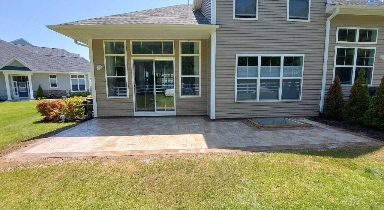 A skilled patio installer reviewing the finished masonry work and joint sand application for a premium home improvement.