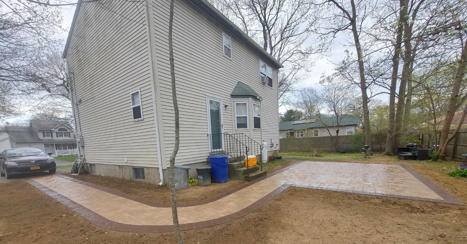 A professional patio installer discussing a stone layout with a client to ensure a high-quality outdoor living space.