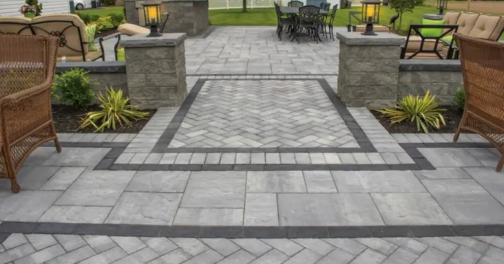 A completed grey-toned patio with a sleek dark border, comparing the finish and durability of Cambridge Pavers vs Nicolock.