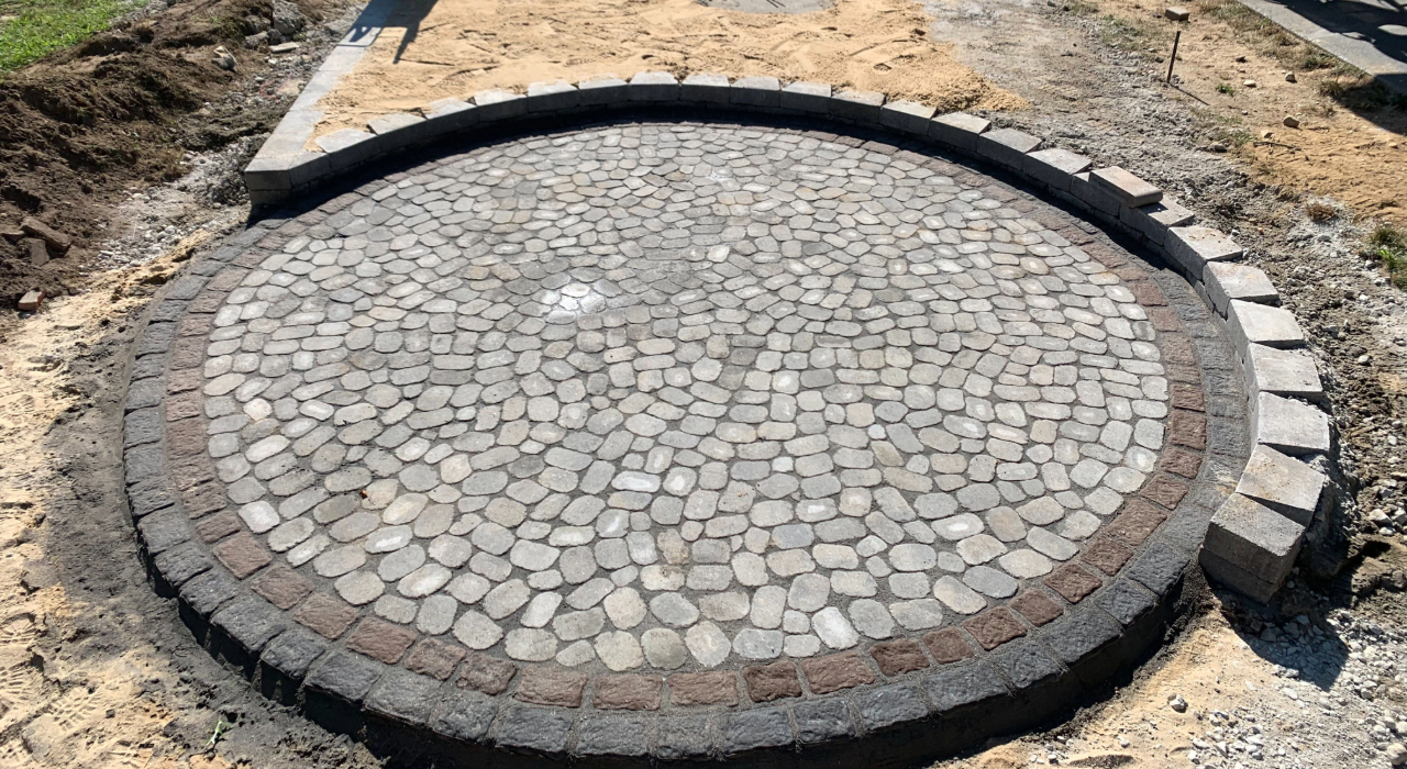 A circular cobblestone pattern under construction, illustrating the different stone shapes available from Cambridge Pavers vs Nicolock.
