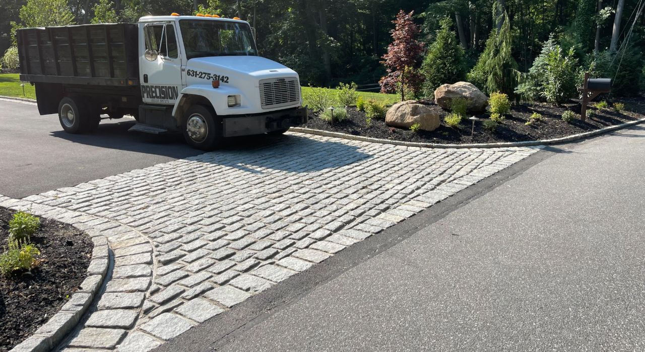 A heavy-duty truck parked on a professionally installed cobblestone entrance, proving the durability of the best pavers for driveways.