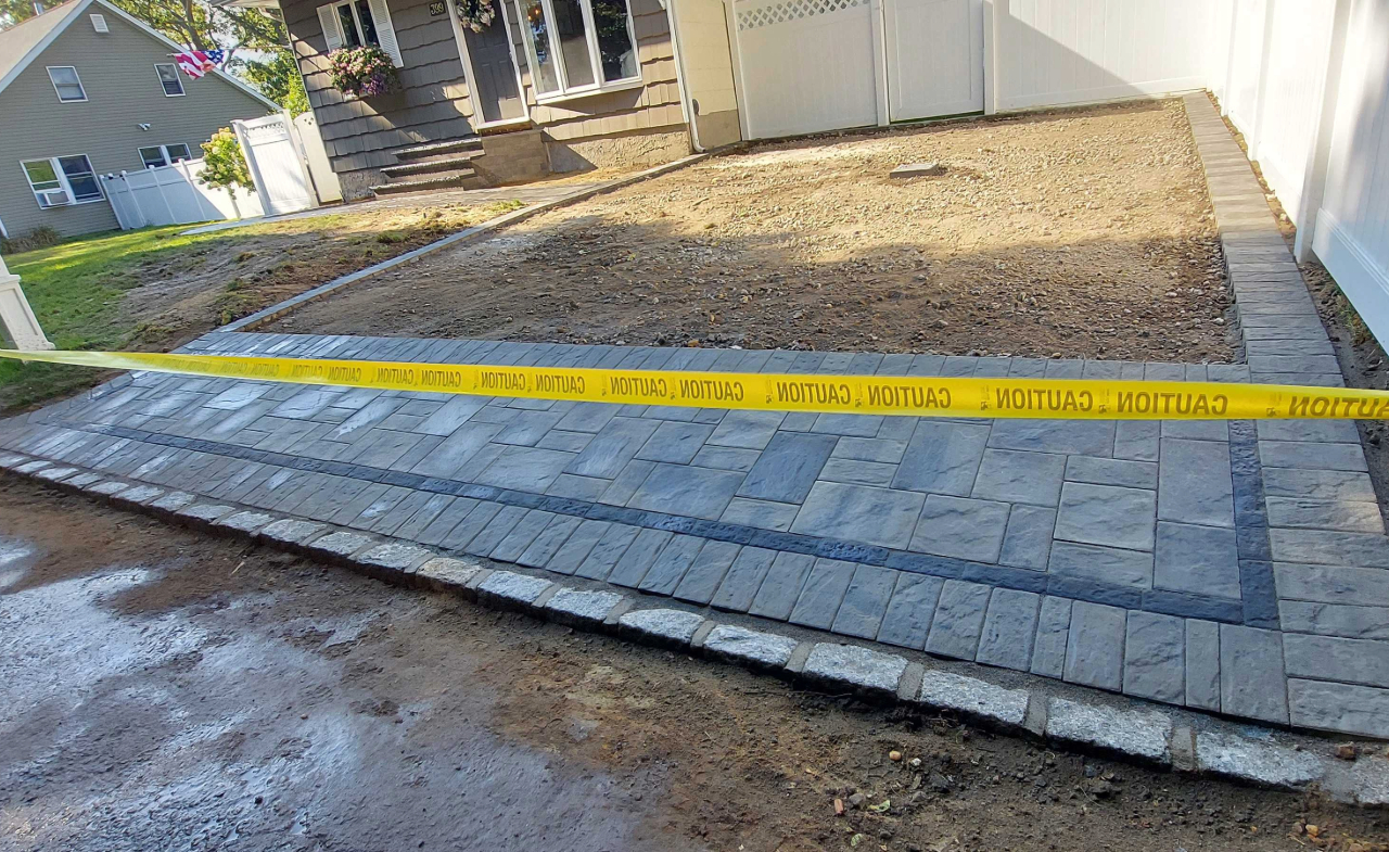A completed interlocking stone entrance secured by caution tape, showcasing the final cost to install a paver driveway.
