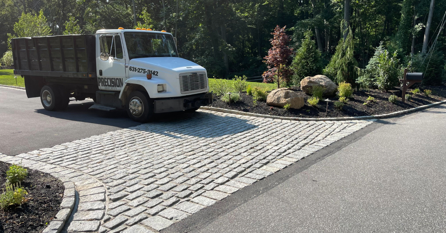 Heavy-duty truck on a finished cobblestone apron, highlighting the durability included in the cost to install a paver driveway.