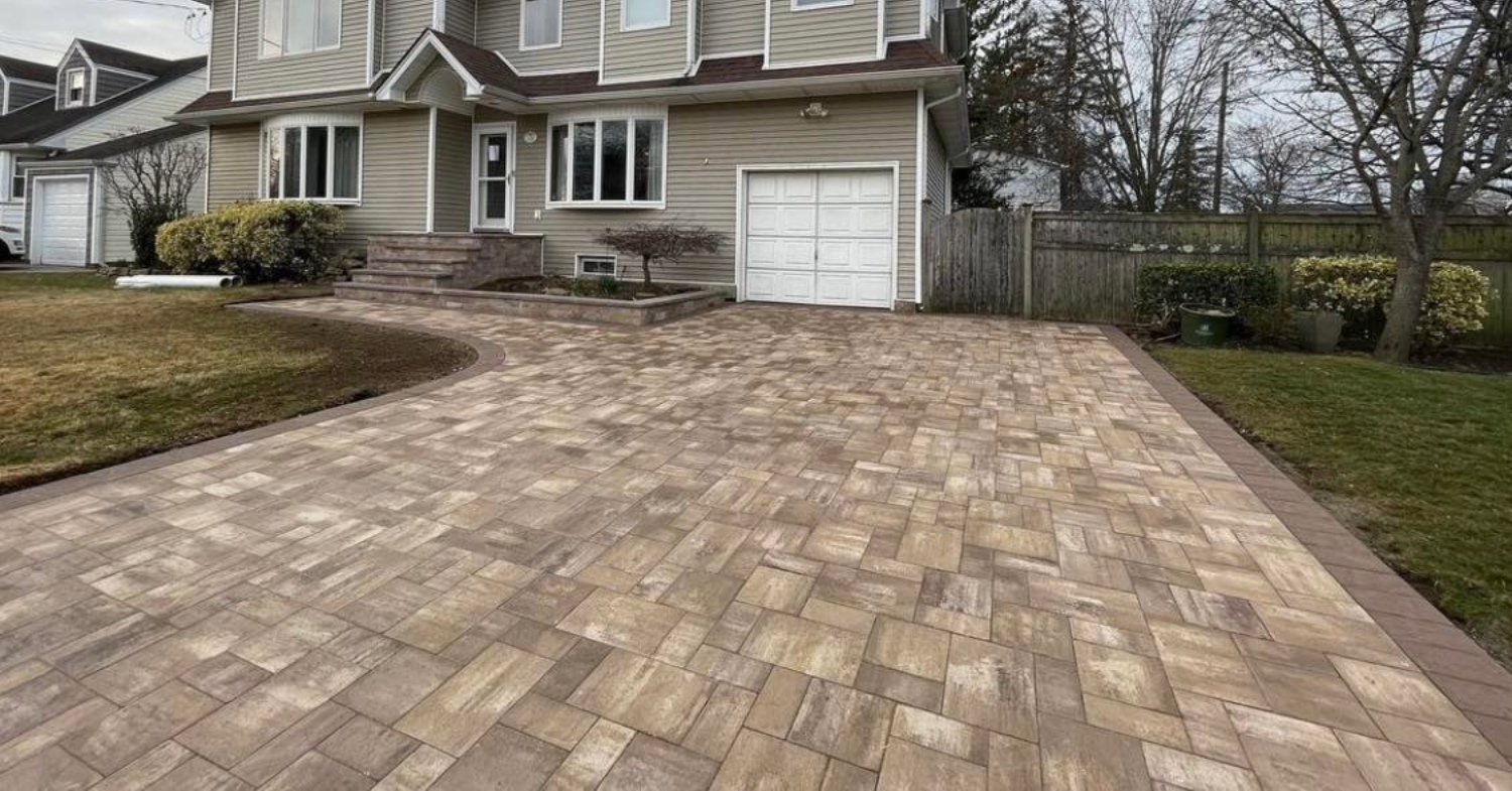 A stunning home exterior featuring a sleek grey and tan entrance, highlighting the driveway paver cost on Long Island.