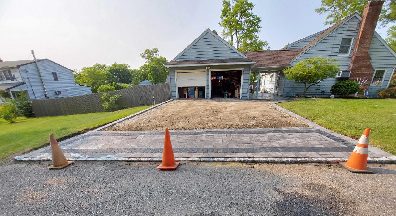 An expansive residential entrance with decorative dark borders, illustrating the factors influencing driveway paver cost on Long Island.