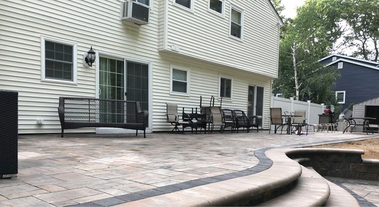 An expansive multi-level stone patio featuring curved steps and outdoor seating for enclosed patio design ideas.