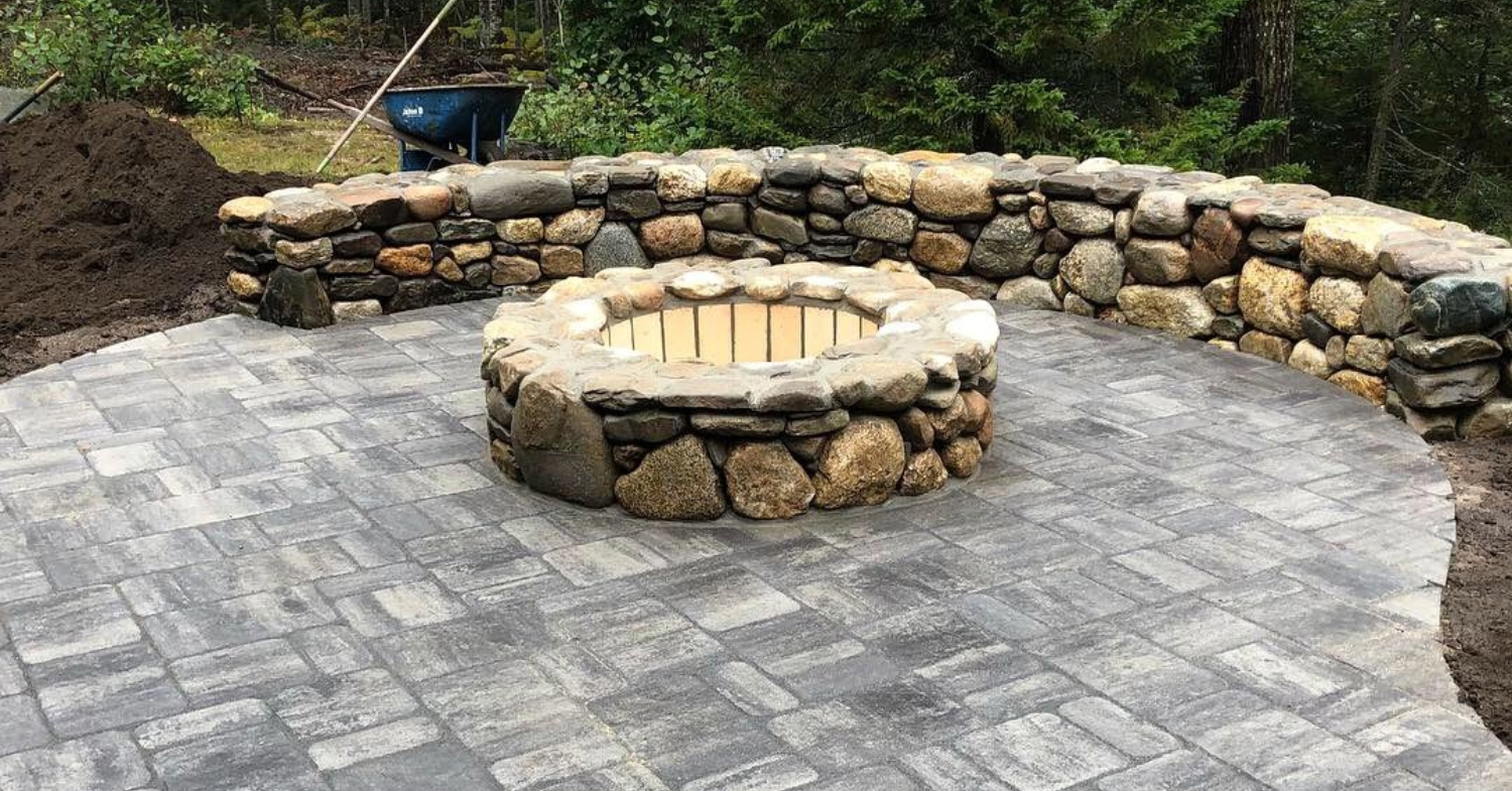 A stylish stone fire pit centered on a spacious paver patio, illustrating the average fire pit installation cost in Nassau County.