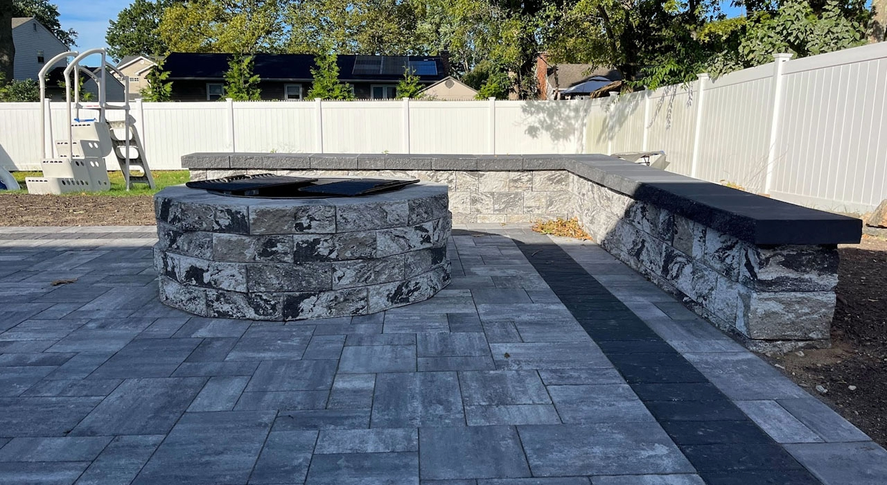 Completed backyard stone fire area with a built-in seat wall, a premium natural gas fire pit installation option.
