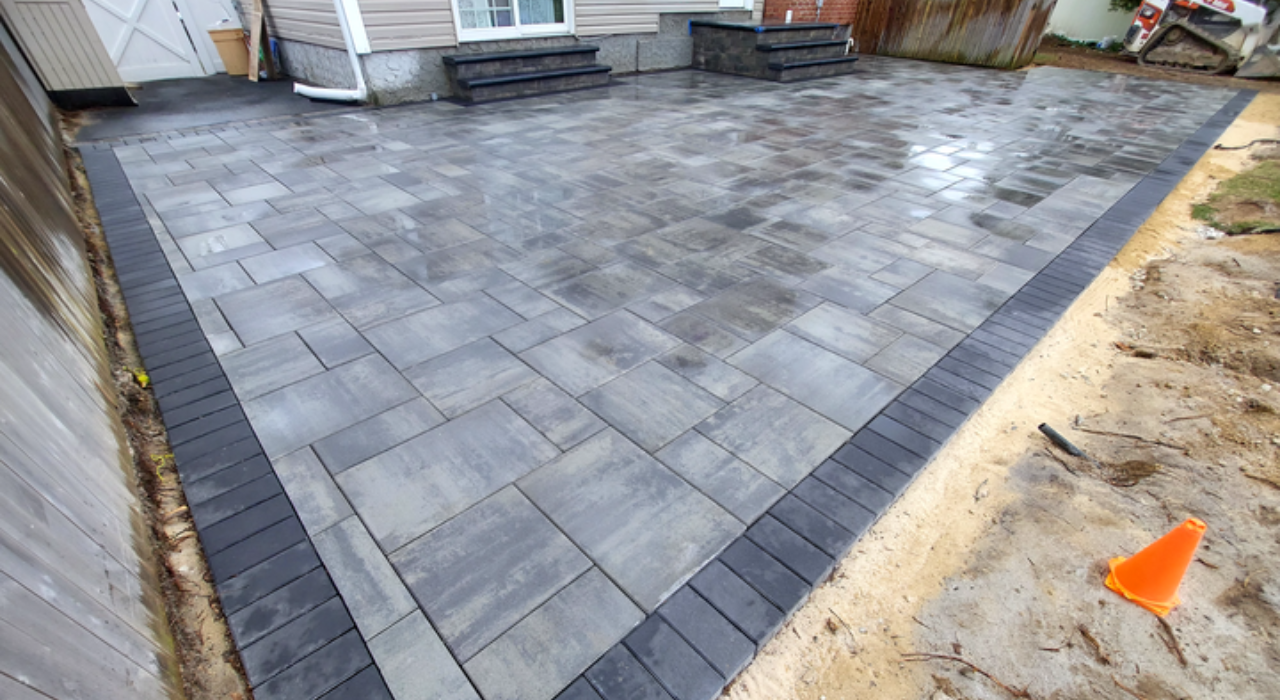 An expansive multi-level stone patio with elegant landscaping, a premium example of the total patio cost in Nassau County.