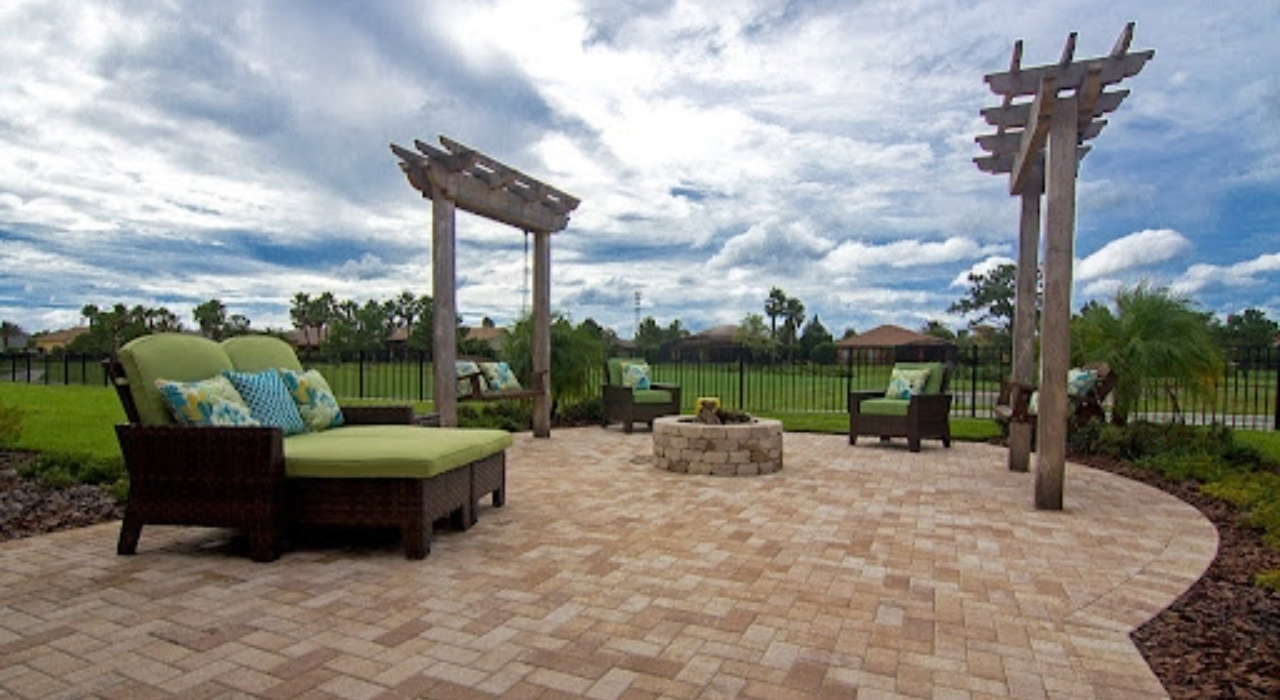 A cozy backyard retreat featuring a stone fireplace and integrated seating walls within an outdoor kitchen and patio design.