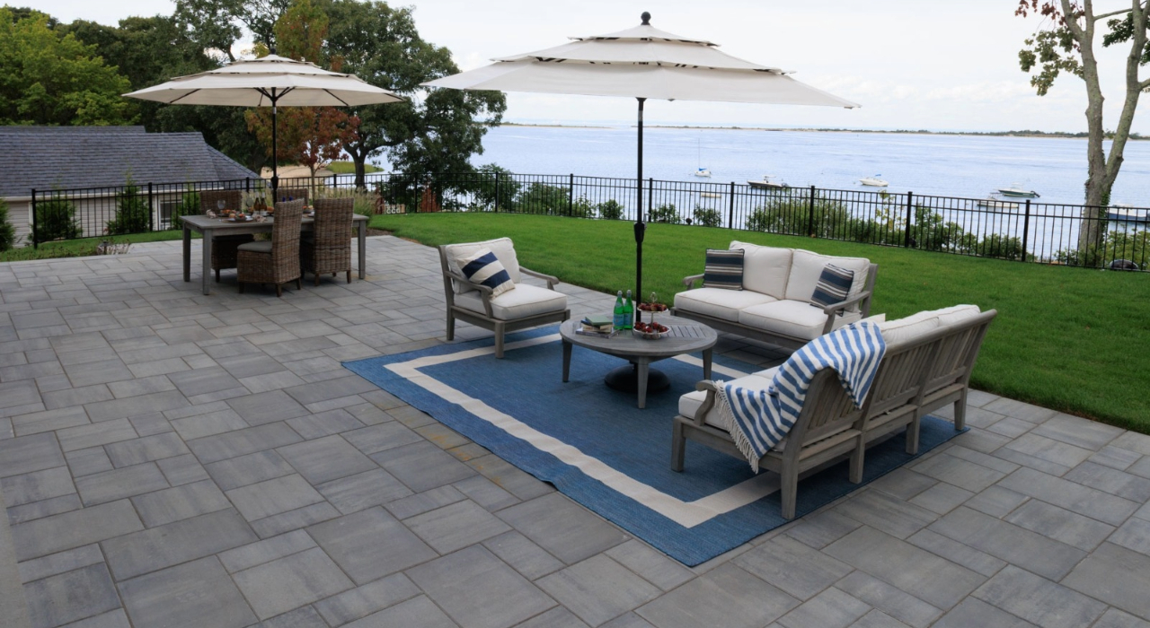 A completed multi-tone stone surface with a dark border, highlighting the custom design options of pavers vs concrete patio.