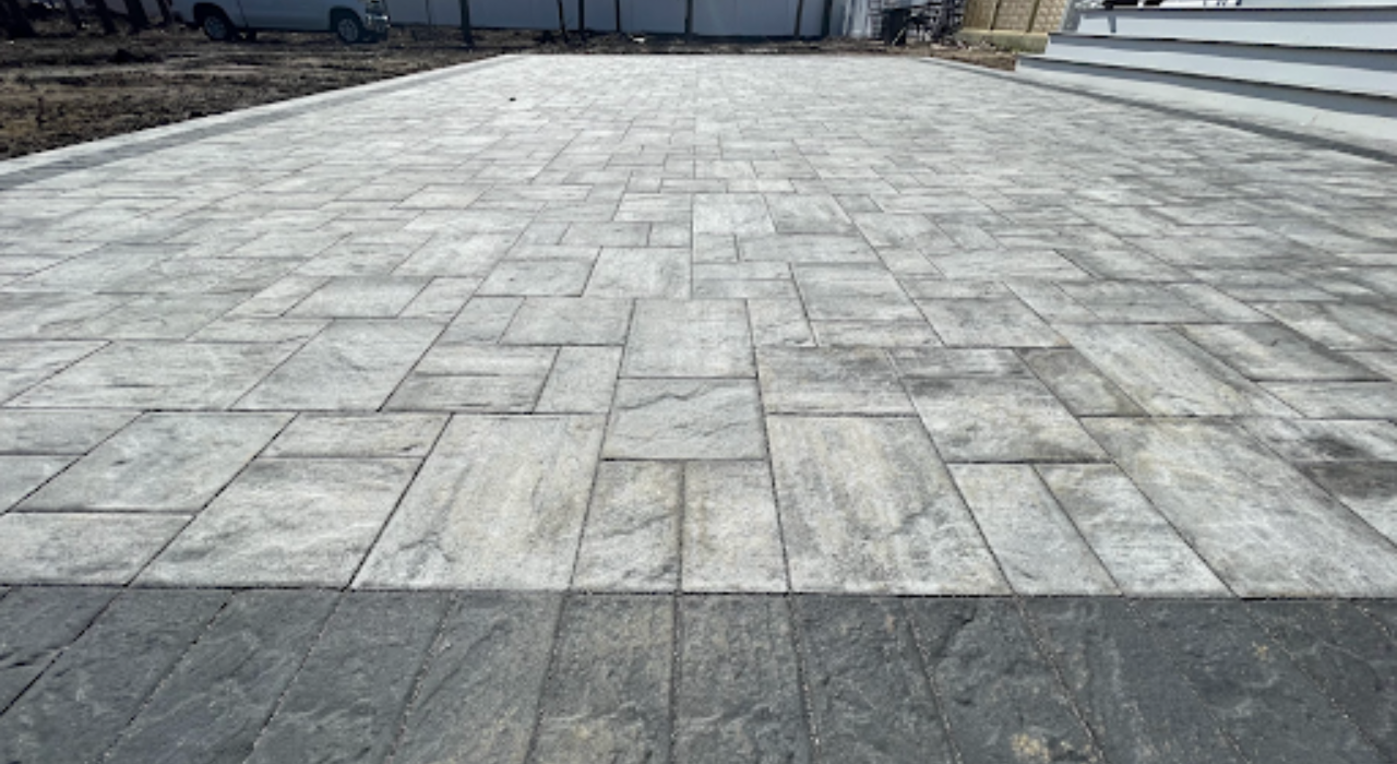 A professional patio contractor using a specialized lifting tool to precisely set stone pavers during a backyard installation.