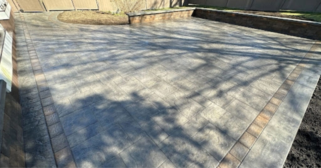 An expansive grey paver area with a sharp black border, showcasing high-end finishes that impact the average cost of a paver patio.