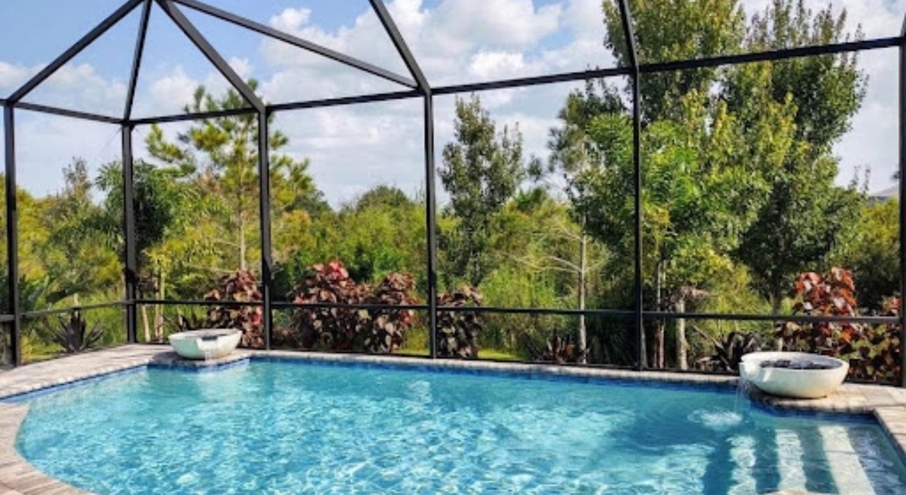 A modern outdoor living space featuring a large swimming pool protected by high-quality custom pool enclosures.