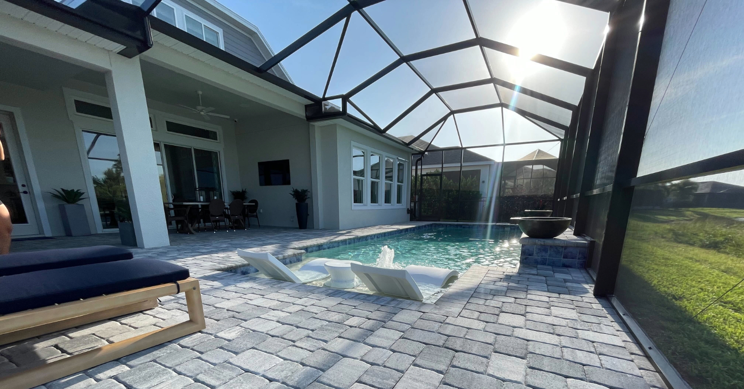 A clear backyard pool area showcasing the structural design and overhead protection provided by custom pool enclosures.