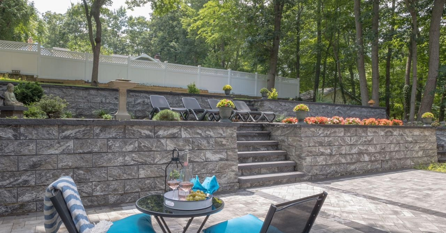 A multi-level grey stone retaining wall featuring integrated steps, showcasing a premium design for retaining wall cost in Nassau County.