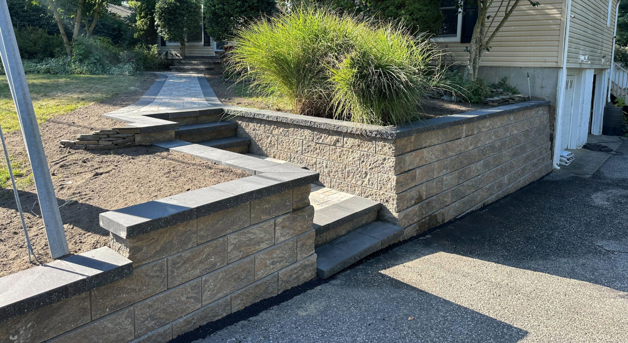 A sturdy stone retaining wall leveling a sloped backyard, providing a clear example for estimating retaining wall cost in Nassau County.