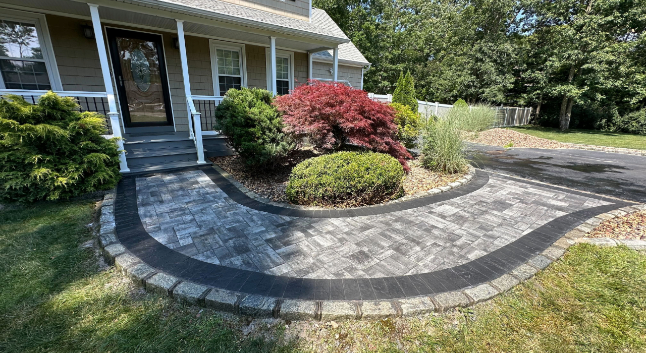 curved paver path leading to a front porch and wrapping around a garden bed, highlighting a professional walkway installation.