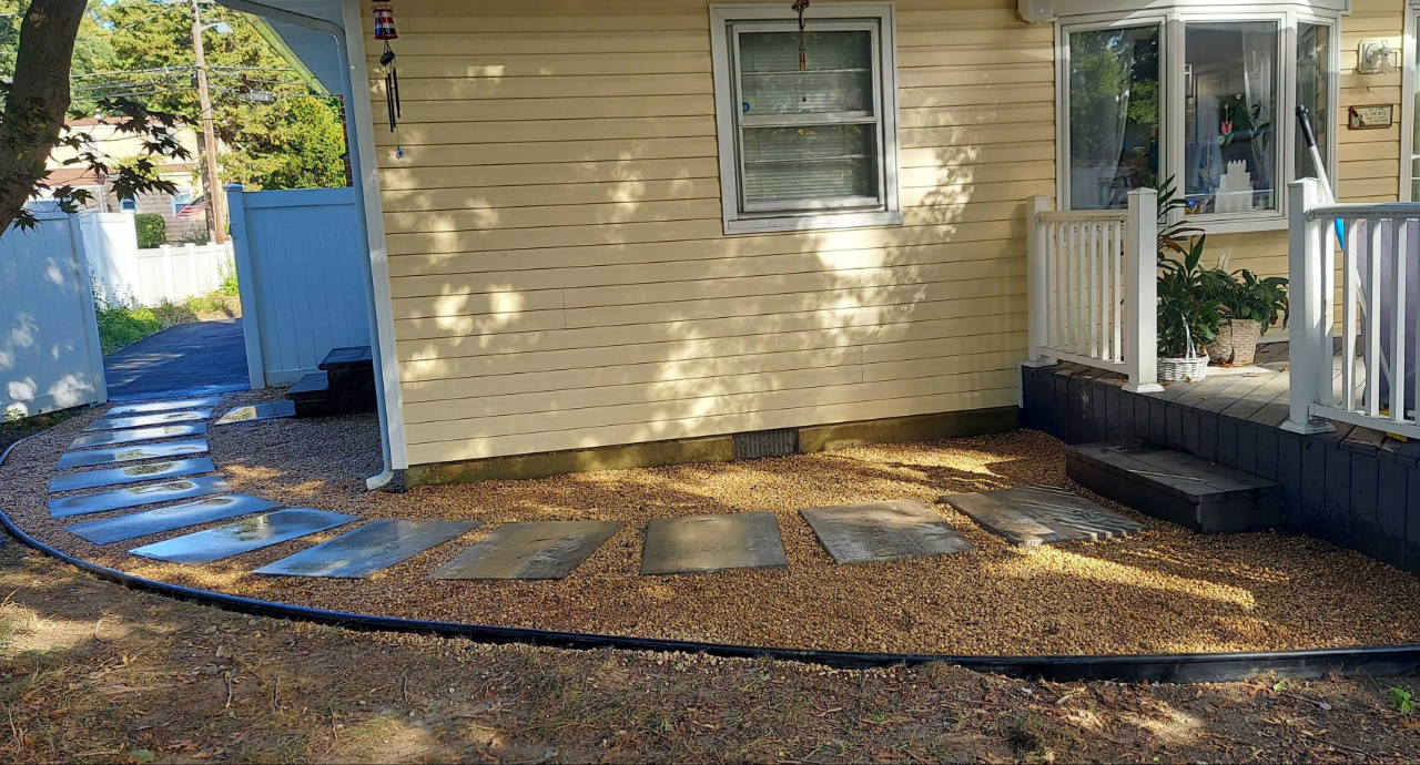 Large slate stepping stones set into a gravel bed, an alternative method for how to install a paver walkway.