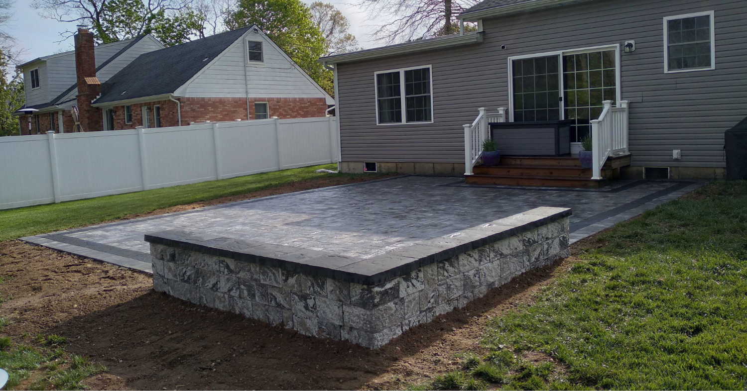 A solid, continuous grey backyard surface showing a functional alternative for homeowners weighing a concrete vs paver patio.